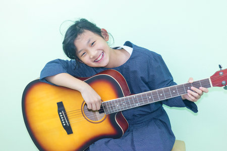 Asian girl playing guitar on green background, education and music concept.の写真素材