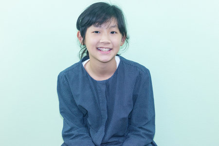Portrait of a cute little Asian girl smiling against a green background
