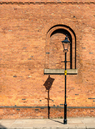 A black lamp post with shadow on wallの写真素材