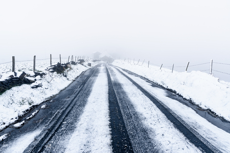 Partially snow covered road with heavy fog at its end, North west England.の写真素材