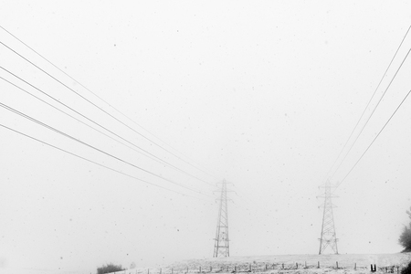 View of power line passing through snowy mistの写真素材