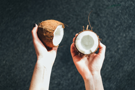 Girl holding half of a coconut isolated darkの写真素材