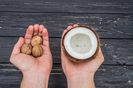Walnuts and coconut in female hands view topの写真素材