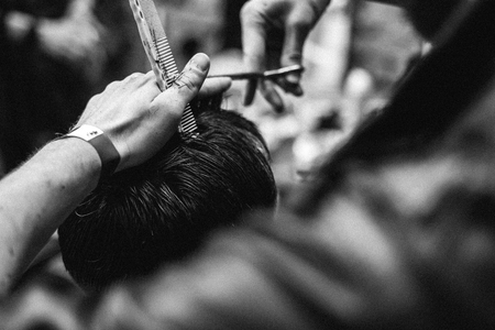 The hands of young barber making haircut in barber shop, black and white photo.の写真素材