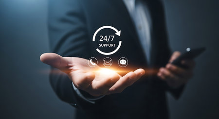 A person in a suit holds out an open palm displaying glowing icons for 24/7 support phone email and chat.の素材
