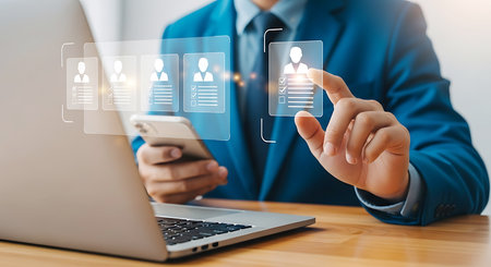 Man in blue suit selects profile from digital interface on desk selectionの素材