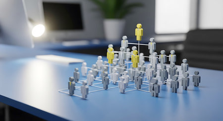 A 3D organizational chart with grey and yellow figures stands on a blue desk. A bright light illuminates the scene.の素材