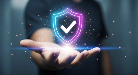 A hand holds a glowing neon shield with a white checkmark inside. Particles and light effects surround the shield.の素材