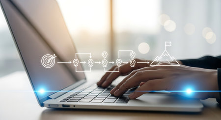 Close-up of hands typing on a laptop with a digital flowchart showing steps from a target to a mountain peak with a flag.の素材