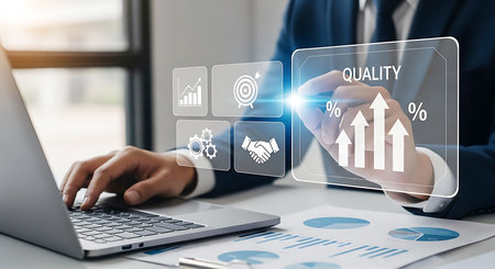 A man in a suit uses a laptop while interacting with a digital interface displaying icons for growth, targets, teamwork, and gears.の素材