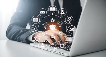 A person in a suit uses a laptop with a glowing digital network of education icons and a graduation cap in the center.の素材