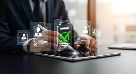 A person in a suit uses a stylus on a tablet displaying a digital interface with document icons and green checkmarks.の素材