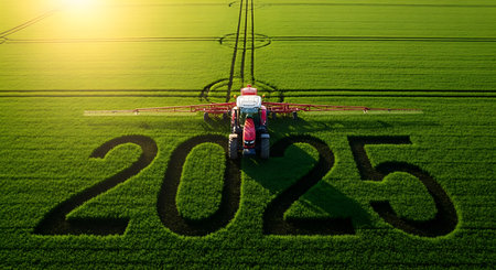 Aerial view of a red tractor spraying a vibrant green field, creating the numbers 2025 in the crop.の素材