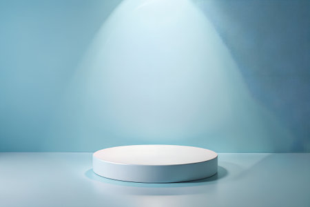 A white cylindrical podium rests on a light blue surface against a matching blue wall. A soft spotlight illuminates the scene from above, casting subtle shadows.の素材