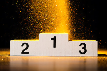 A white three-tiered podium with numbers 1 2 and 3 stands against a black background. Gold glitter cascades down onto the first place step.の素材