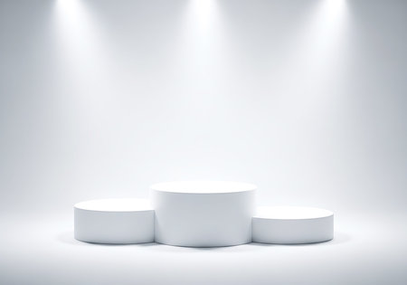Three white cylindrical podiums of varying heights are arranged on a light gray surface. Spotlights illuminate the scene from above.の素材