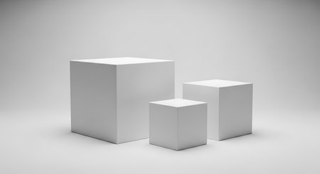 Three white geometric cubes of different sizes are arranged on a light gray studio background with subtle shadows.の素材