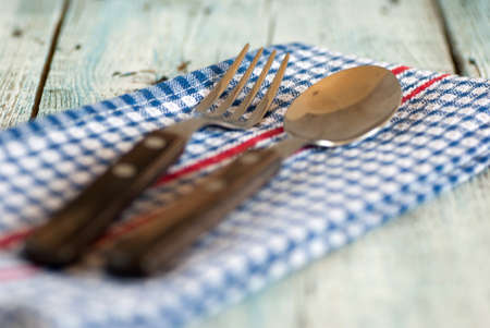 Spoon and fork with dish towel on old wooden tableの写真素材