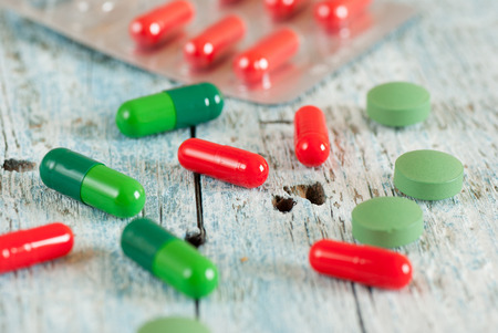 Green and red pills on old wooden tableの写真素材