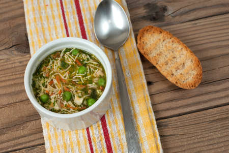 Soup with pasta and vegetables on old wooden tableの写真素材