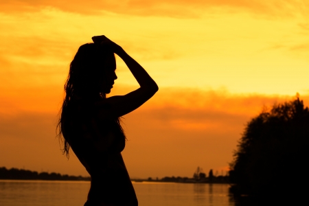 Beautiful dancing woman hands up sunset silhouetteの写真素材