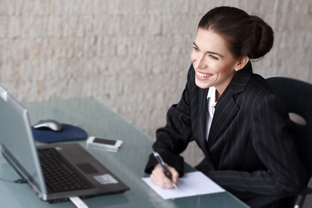 Brunette businesswoman with teeth smile writing with pen の写真素材
