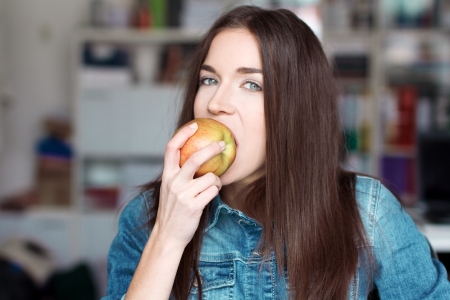 Brunette woman eating apple and lookingの写真素材