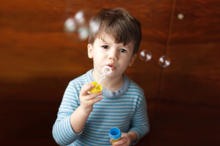 Cutle little boy blowing bubbles at homeの写真素材