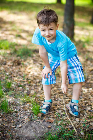 Cute boy drawing into the soil at parkの写真素材