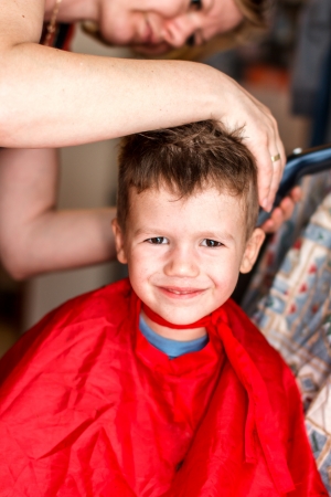 Mother cutting hair for son, smileの写真素材