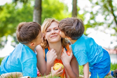 Little sons hug mother, happy family, outdoorの写真素材