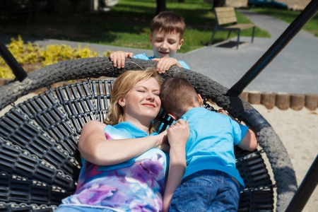 Happy mother with kids laying in saucer swingの写真素材