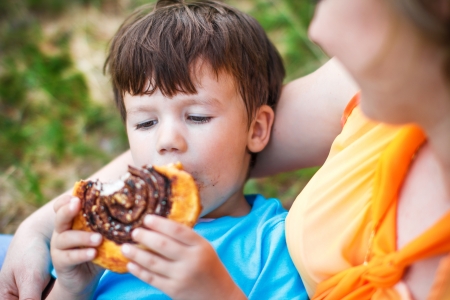 Happy mother with son eating cocoa donutの写真素材