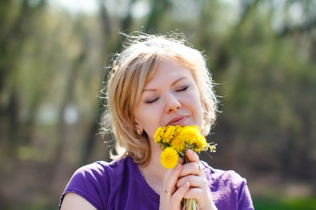 Blonde young woman smell dandelions flowersの写真素材