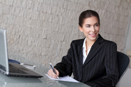 Young brunette businesswoman with laptop and smartphone, officeの写真素材