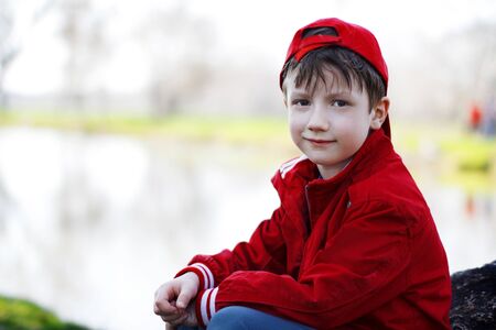 Little child sitting on stone at river, natureの写真素材