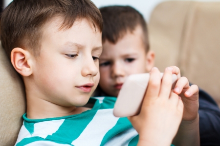 Little boys playing on smartphone, indoorの写真素材