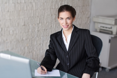 Successful businesswoman with teeth smile in office, signing documentの写真素材