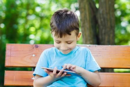 Young boy sitting on bench with tabletの写真素材