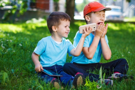 Young boys with wireless tablet and smartphone at parkの写真素材