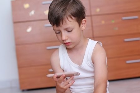 Boy with smartphone at home playingの写真素材
