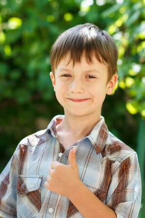 Little preschooler boy thumb up outdoor, successの写真素材