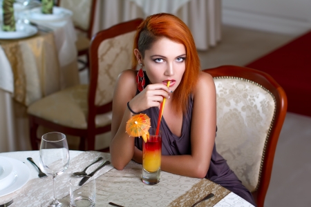 Sexy redhead woman drinking juice in restaurant, indoorの写真素材