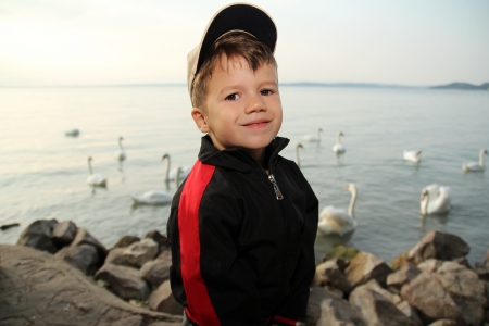 Little boy at lake with swan in sunrise, Balaton, Hungaryの写真素材
