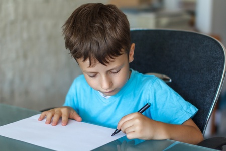 Little boy writing on blank paperの写真素材