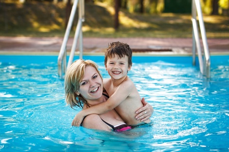 Happy blonde mother with little son in poolの写真素材