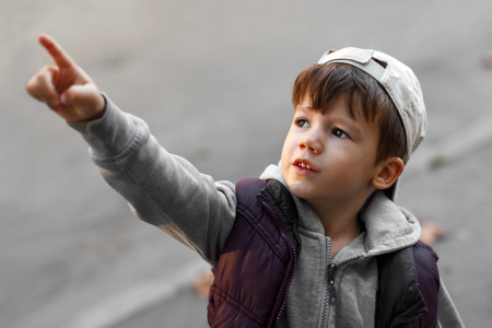 Little boy in cap pointing up, outdoor