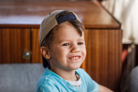 Happy little boy in cap teeth smile indoorの写真素材