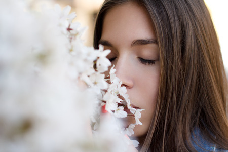 Young brunette woman smelling cherry tree, outdoorの写真素材