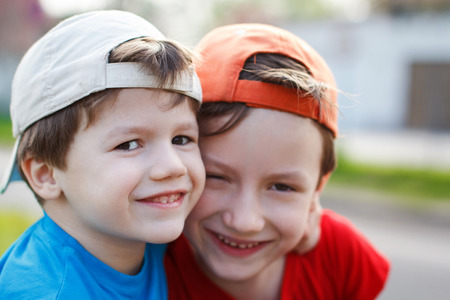 Smiling caucasian brothers in cap, outdoor portrait